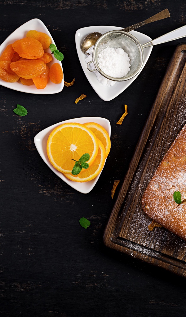 Свежий сладкий пирог на столе с курагой и апельсином