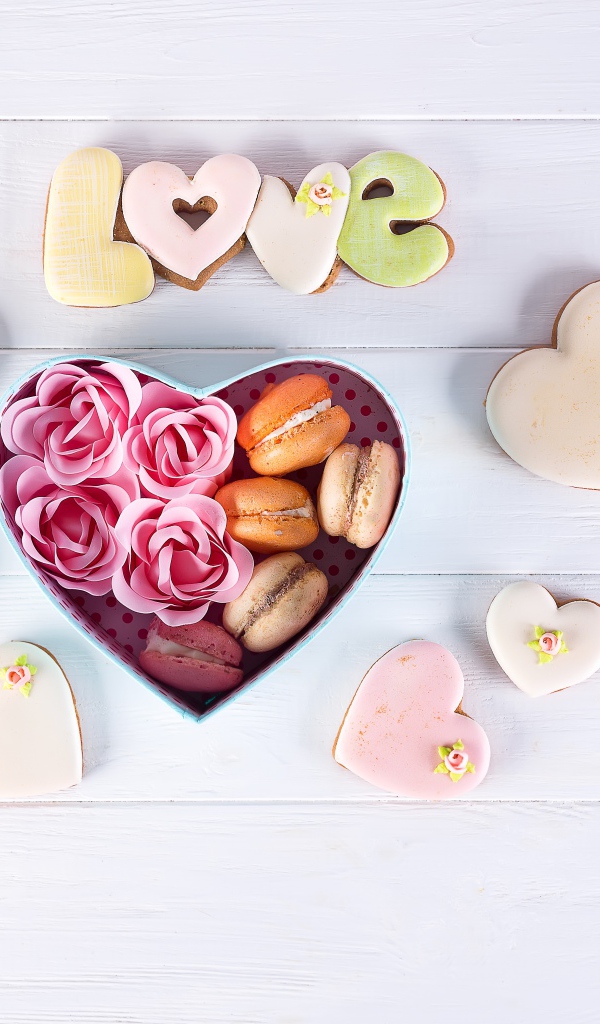 Печенье в форме сердца на столе с коробкой с десертом макарун