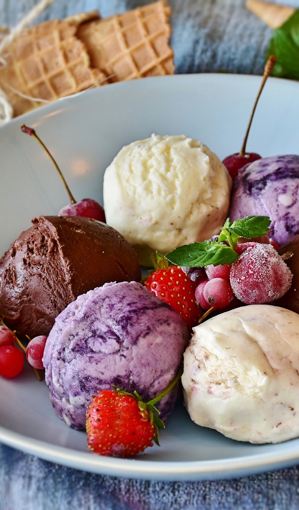 Шарики фруктового мороженого на тарелке со свежими ягодами