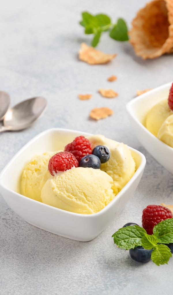 Шарики мороженого с ягодами на столе с вафельными рожками