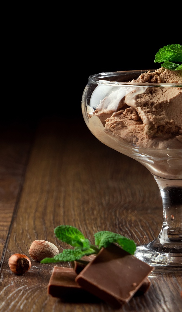 Кофейное мороженое в креманке на столе с шоколадом и орехами