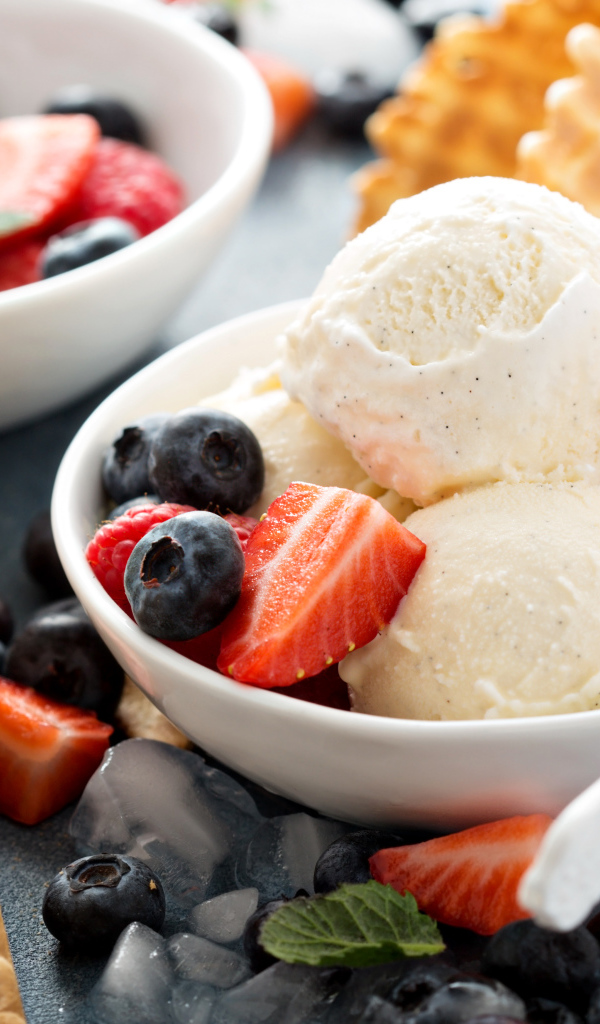 Мороженое с ягодами черники и клубники на столе с вафельными рожками