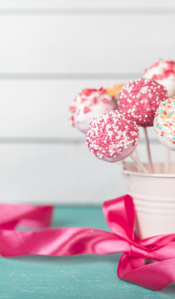 Леденцы в стакане на столе с розовым бантом из ленты