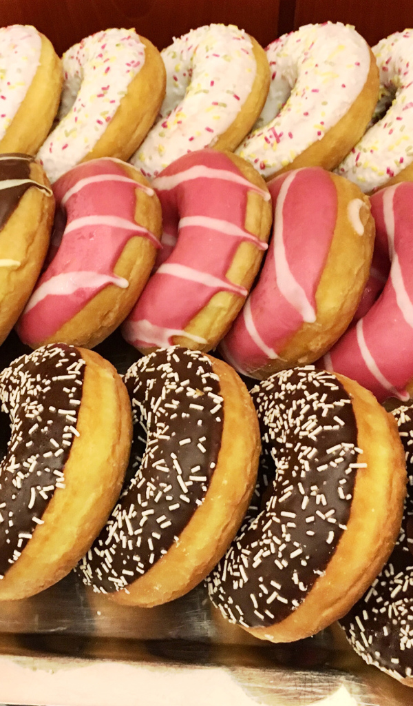 Много вкусных сладких пончиков с глазурью на столе 