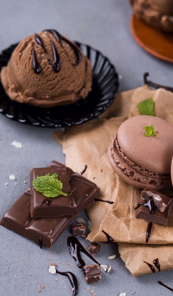 Печенье макарун на серой поверхности с мороженым и шоколадом