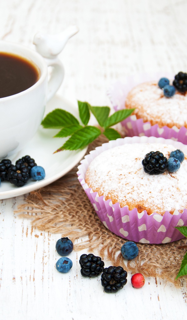 Кексы с сахарной пудрой и ягодами на столе с какао