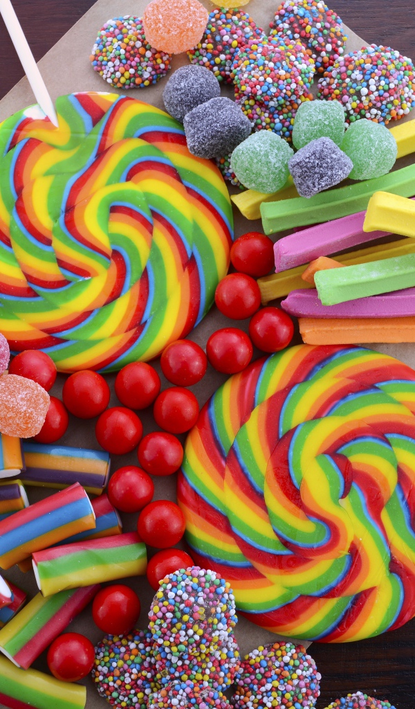 Разноцветные желейные конфеты, мармелад и леденцы на палочке на столе