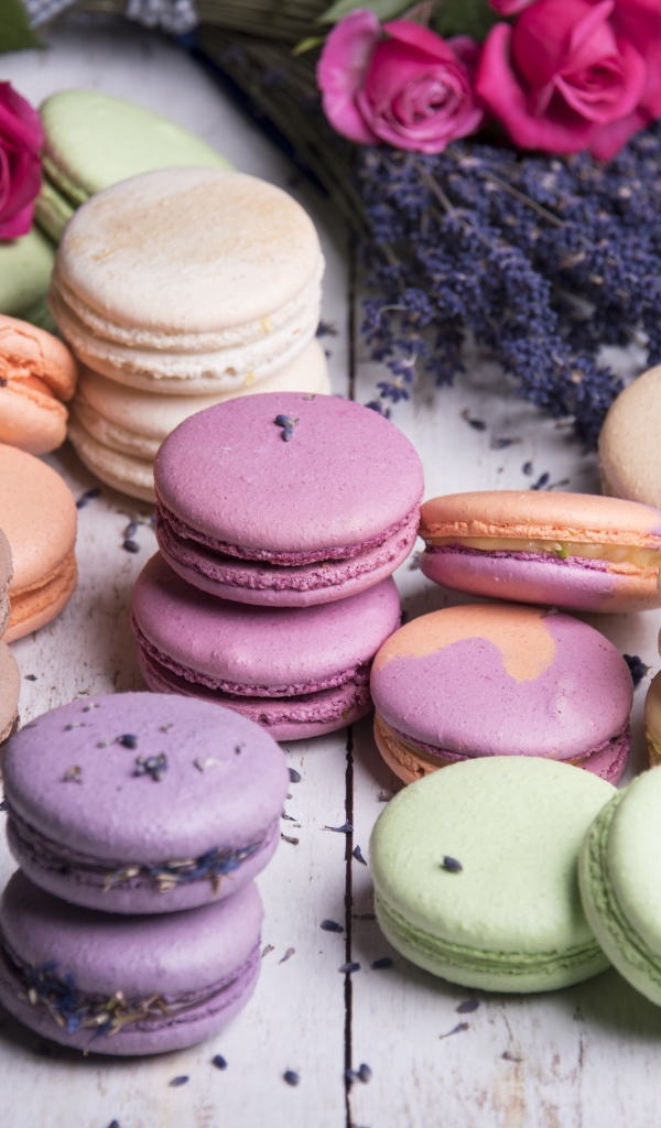 Разноцветный десерт макарон на столе с лавандой и розами