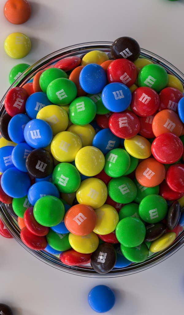 Разноцветные конфеты с миске на сером столе