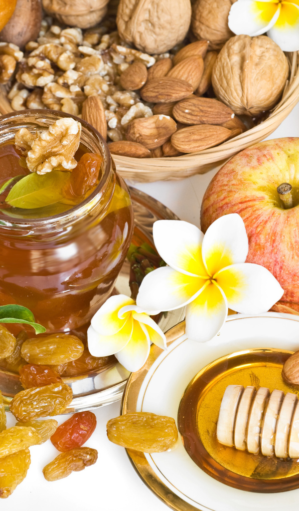 Орехи, мед, яблоки и выпечка с изюмом на столе к празднику