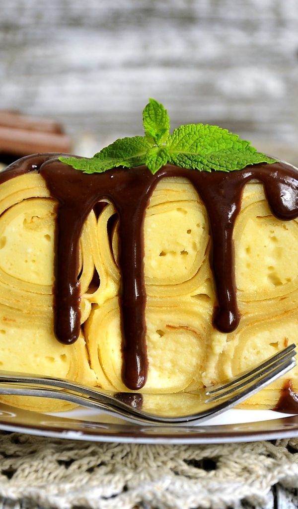 Блинный торт с творогом и шоколадом на тарелке 