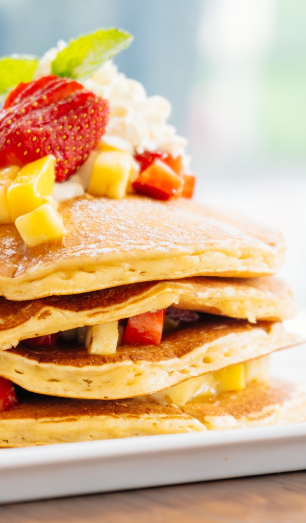 Оладьи с сахарной пудрой, сливками и кусочками клубники и ананаса