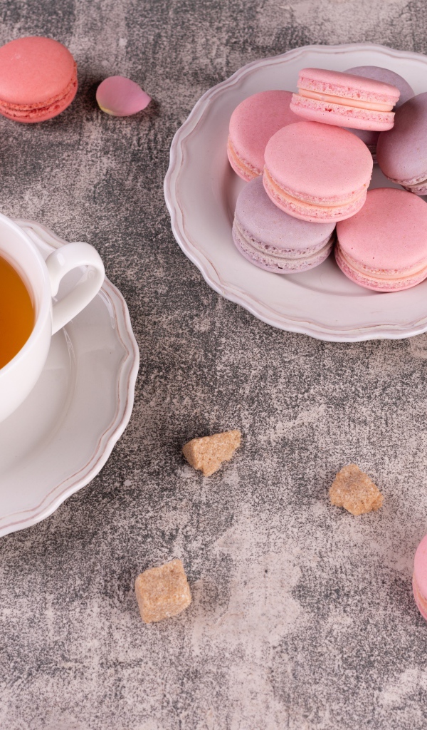 Тарелка с десертом макарун на столе с чашкой чая
