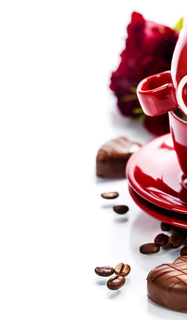 Красные чашки на белом фоне с шоколадными конфетами и кофейными зернами
