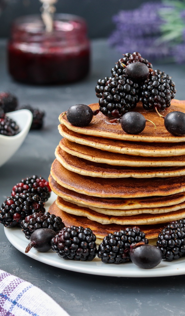Румяные оладьи на тарелке с ягодами черники и смородины