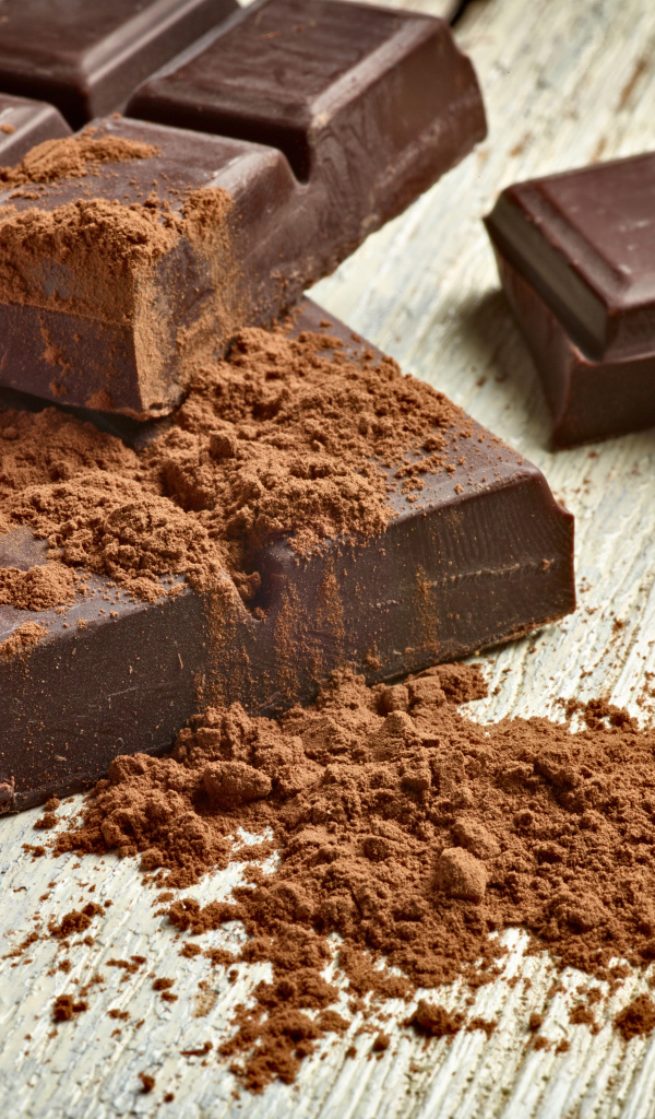 Куски шоколада с какао на деревянном столе 