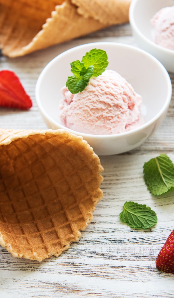 Клубничное мороженое на столе с рожками и клубникой