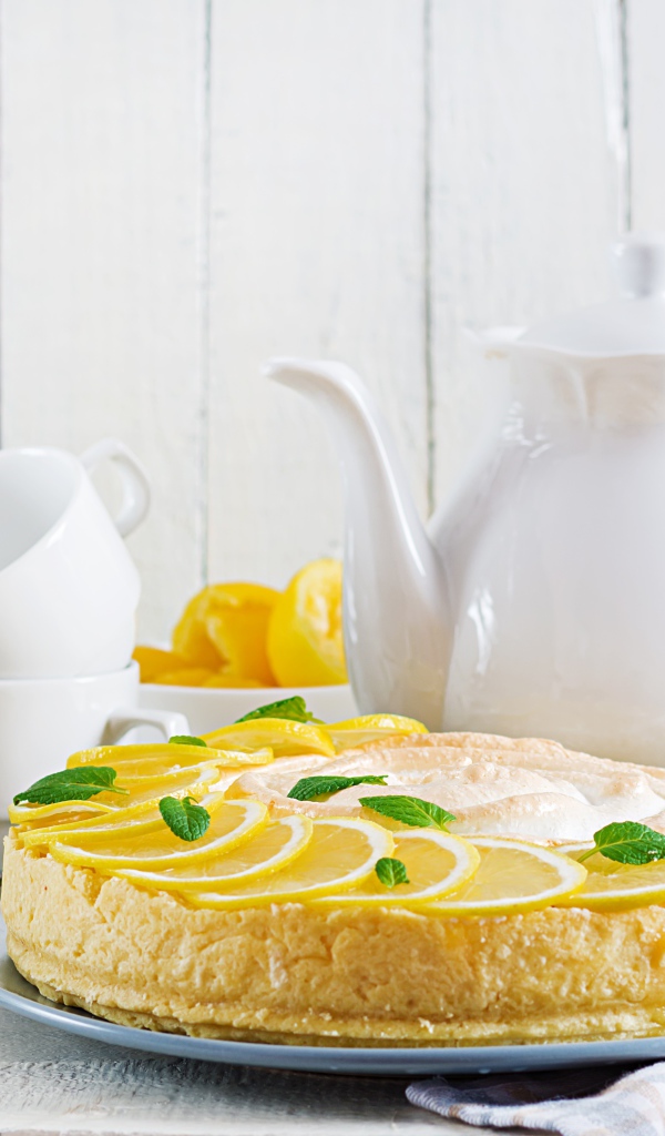 Вкусный песочный пирог с лимоном на столе с чашками и чайником