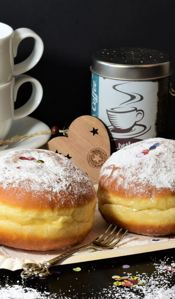 Два пончика с сахарной пудрой на черном фоне с белыми чашками