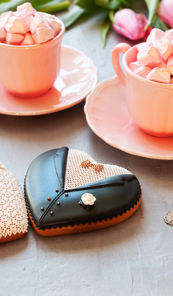 Две розовые чашки с маршмеллоу на сером фоне с печеньем и тюльпанами