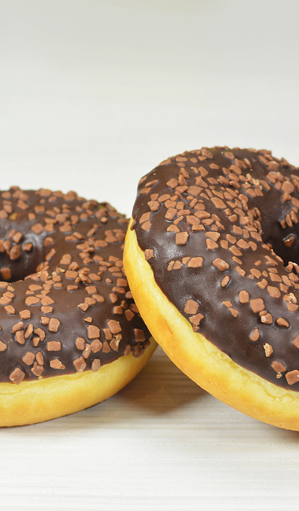 Два сладких пончика с шоколадом на сером фоне