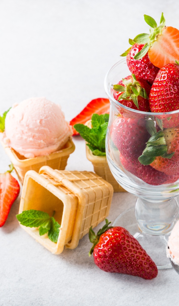 Вафельные стаканчики с мороженым на столе со свежей клубникой