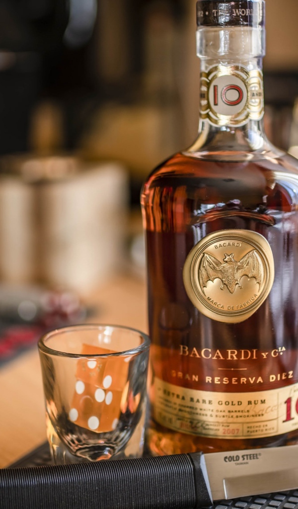 Бутылка виски на столе с рюмкой и ножом