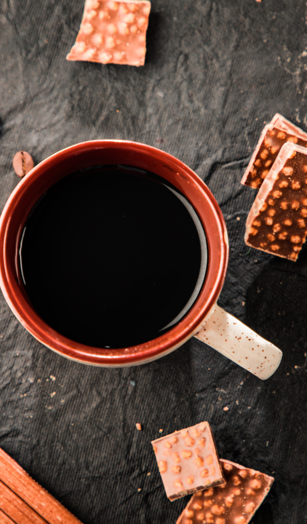 Чашка кофе на столе с кусочками шоколада и кофейными зернами