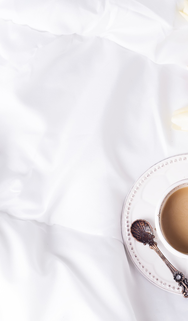 Чашка кофе на белом покрывале с тюльпанами