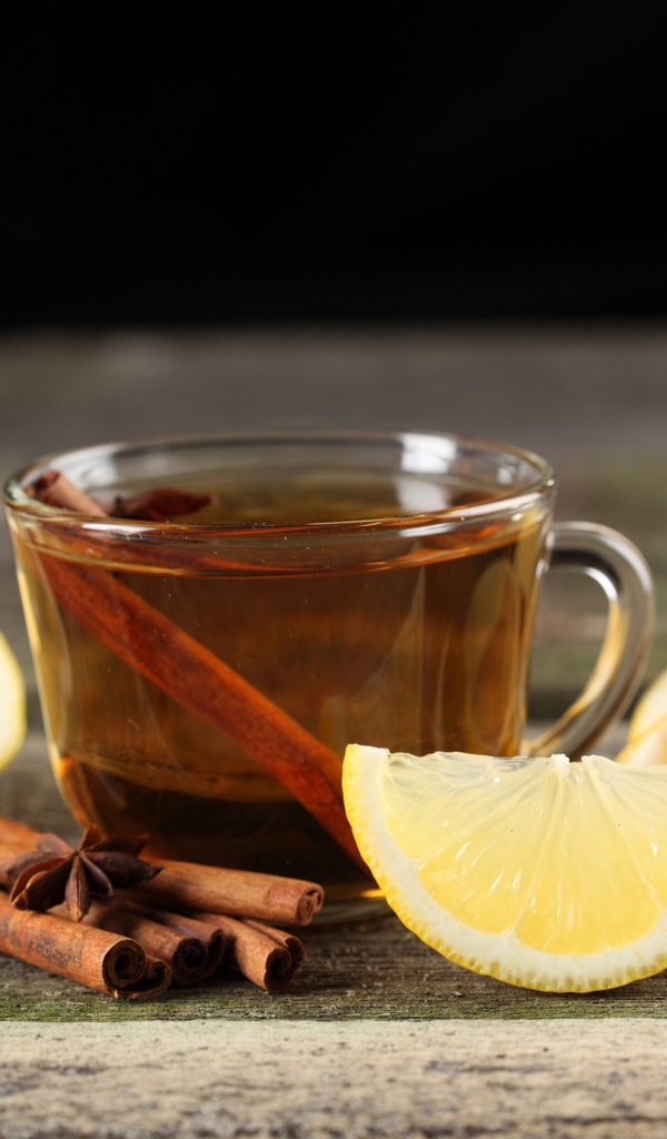 Чашка чая на столе с корицей и кусочками лимона 