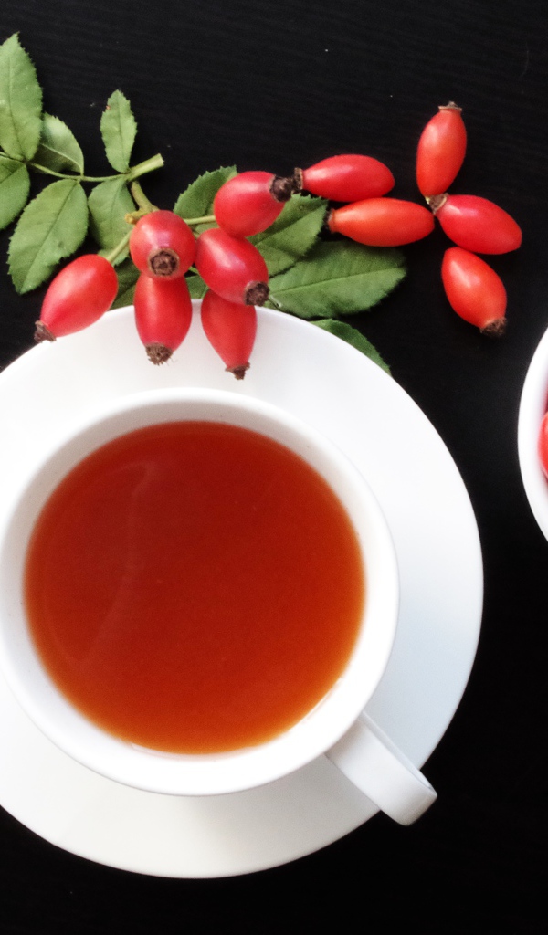 Чашка чая на столе с ягодами шиповника