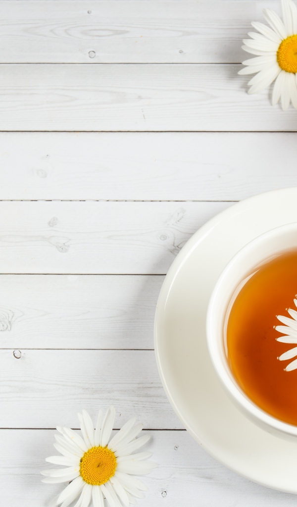 Чашка чая с ромашкой на столе с медом