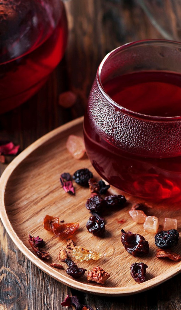 Стеклянная чашка горячего красного чая с сухофруктами 