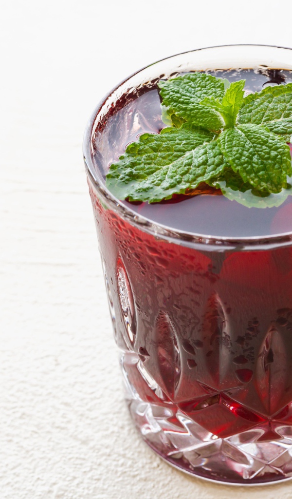 Стакан вишневого сока с мятой на белом фоне