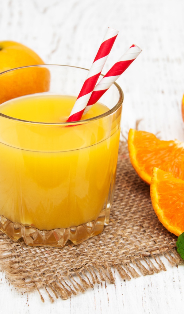 Стакан свежего сока на столе с апельсинами