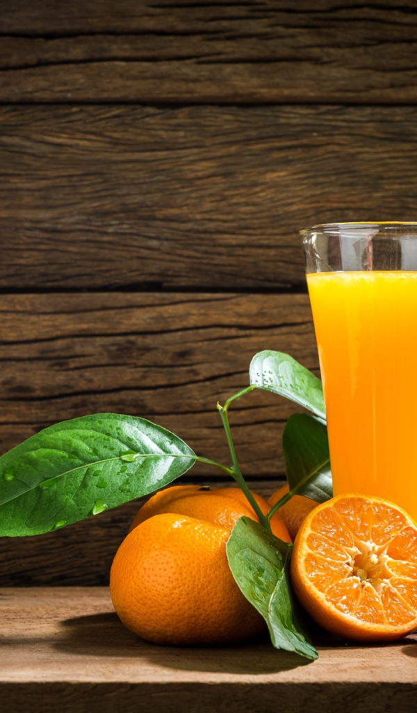 Стакан апельсинового сока на столе с мандаринами