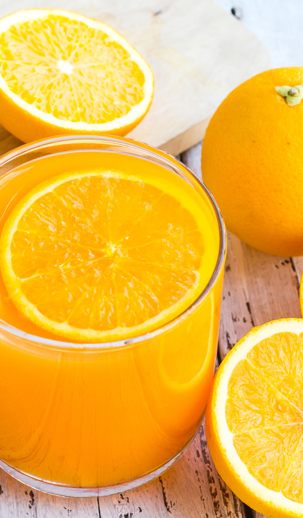 Стакан апельсинового сока на столе со свежими апельсинами на столе