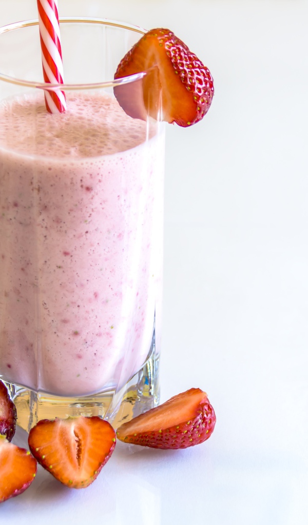 Стакан клубничного смузи на белом фоне с ягодами