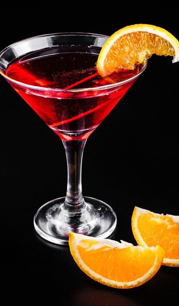 Алкогольный коктейль с кусочками апельсина на черном фоне