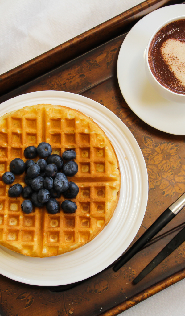 Капучино в чашке на подносе с вафлями и черникой 