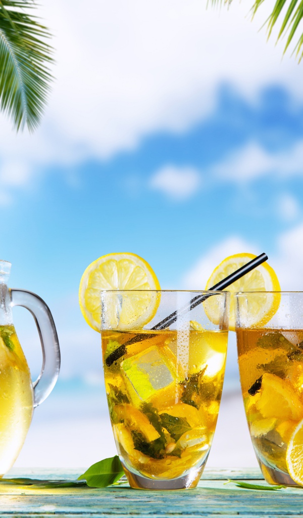 Графин и два стакана лимонада на столе на тропическом пляже