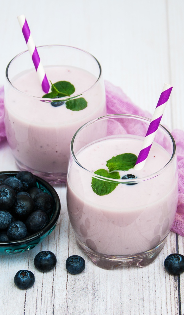 Коктейль в стаканах на столе с ягодами черники