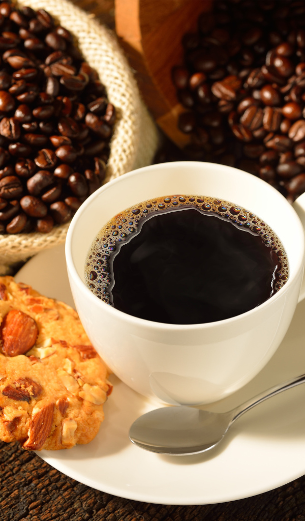 Кофейные зерна на столе с белой чашкой и печеньем