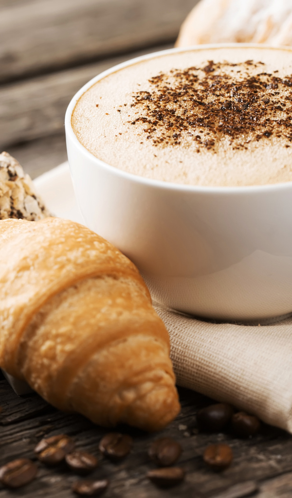 Чашка капучино на столе круассанами