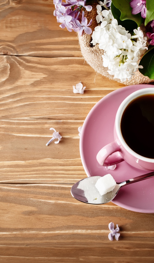 Чашка кофе на деревянном столе с сиренью 