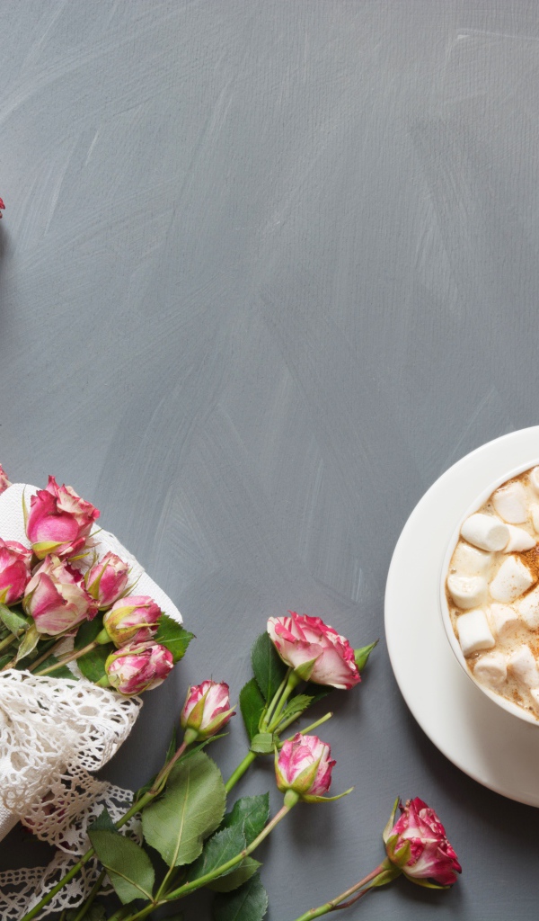 Чашка кофе с маршмеллоу на столе с подарком и букетом роз