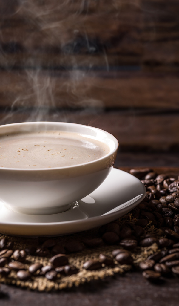 Чашка горячего ароматного кофе на столе с зернами