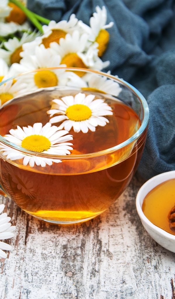 Чашка чая на столе с медом и букетом ромашек