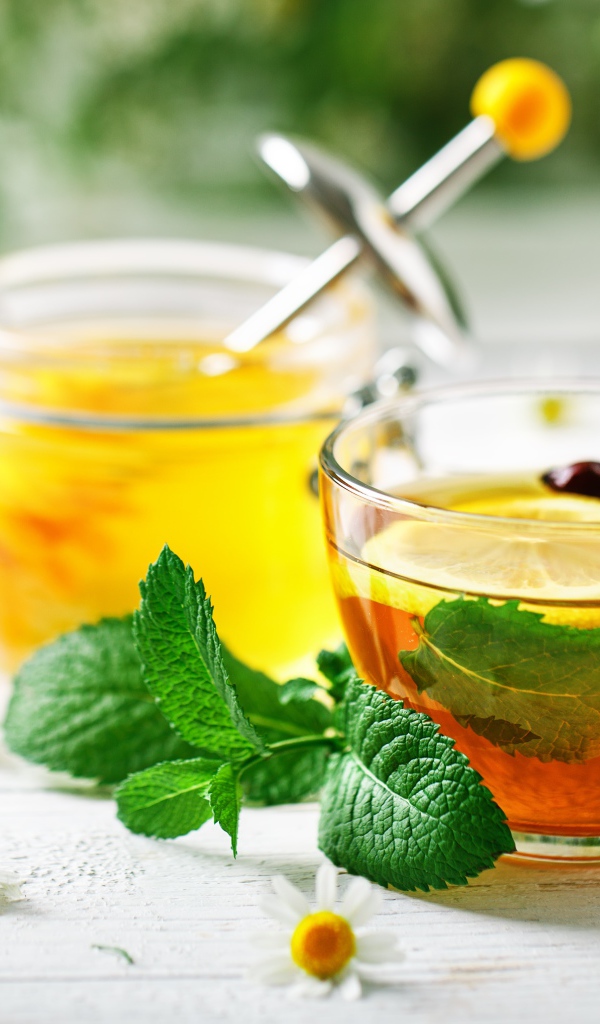 Чашка чая с лимоном и мятой на столе с медом