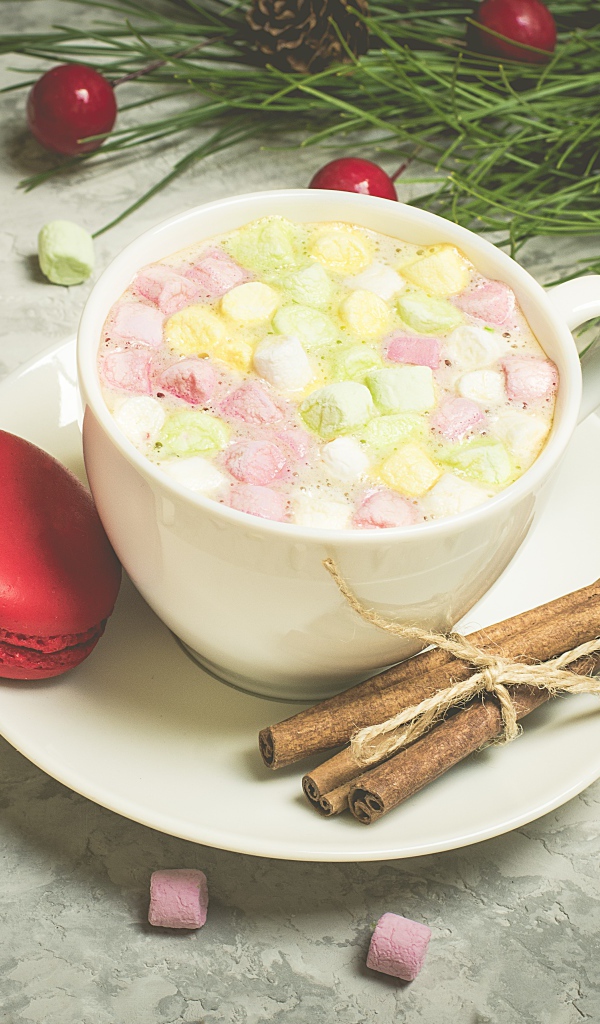 Напиток с маршмелоу на блюдце с макаруном и корицей